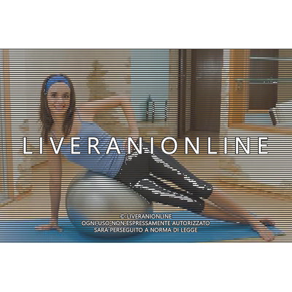 DONNA - FITNESS - GINNASTICA - AEROBICA -RILASSAMENTO Young happy woman doing fitness exercises at home © AG. ALDO LIVERANI SAS