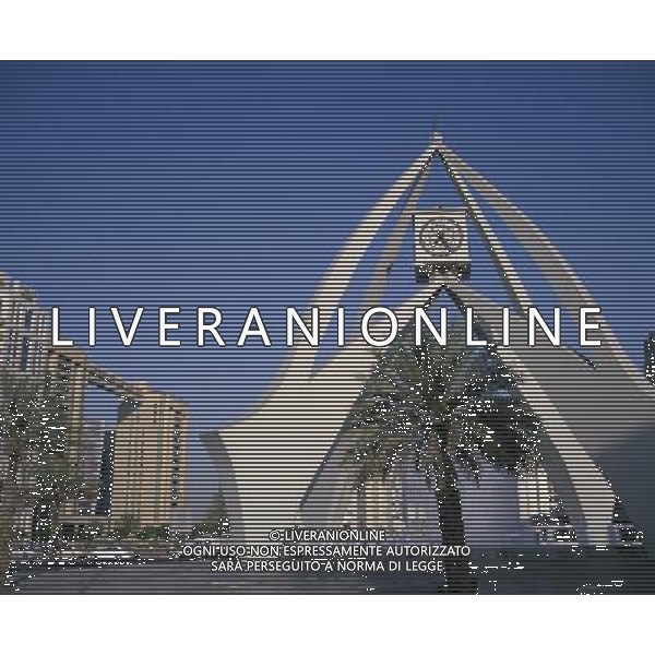 Dubai Clock Tower. Modern sculptural structure with pool and fountains below and palm tree in foreground. Traffic and city buildings behind. Dubayy United Arab Emirates Ref: B529_105406_005687 Compulsory Credit: Photoshot. DUBAI - EMIRATI ARABI UNITI /Agenzia Aldo Liverani Sas - ITALY ONLY -