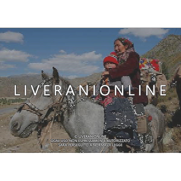 (100914) -- ALTAY, Sept. 14, 2010 -- A herdswoman of Kazak ethnic group rides a horse with a child while transferring to autumn meadows in Altay, northwest China\'s Xinjiang Uygur Autonomous Region, Sept. 14, 2010. The herdsmen of Kazak ethnic group in Xinjiang began to transfer their properties to autumn meadows after more than three months of herding lives in summer meadows. Ye Erjiang) (zn) ©photoshot/Agenzia Aldo Liverani Sas - ITALY ONLY - Gruppo di pastori di etnia Kazak trasferiscono i loro bovini e ovini nei prati per il pascolo dell\'autunno Altay, nord-ovest della Cina Xinjiang Uygur Regione Autonoma, 14 settembre 2010.