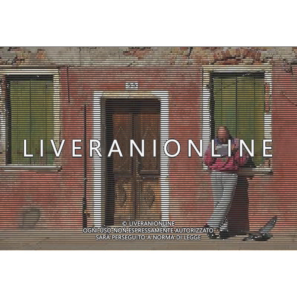 (110309) -- VENICE, March 9, 2011 () -- A local resident reads a letter in front of a brightly-painted house at Burano, an outlying island northeast of Venice, Italy, March 8, 2011. Villagers of the island have a long tradition to paint their houses colorfully, which today have become the main feature of the island. (/Wang Qingqin) (wjd) Vista della citta\' AG. ALDO LIVERANI SAS ITALY ONLY *** Local Caption *** .