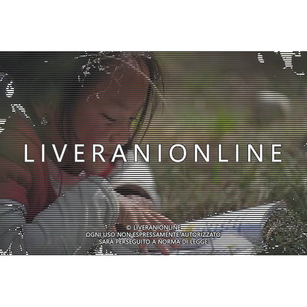 (110517) -- BEIJING, May 17, 2011 () -- Nyimazhoi, a villager of Lhoba ethnic group, reads a book at a Lhoba primary school in Nanyi Lhoba Ethnic Township, in Mainling County of southwest China\'s Tibet Autonomous Region (TAR), May 11, 2011. Located at the foot of snow-peaked mountains near the south border between China and India, the Nanyi Township of Qionglin Village, a tranquil and picturesque place, is inhabited by people of Lhoba ethnic group. With a total of 2900 people, Lhoba ethnic group is the smallest among China\'s 56 ethnic groups in term of population. The family of forty-six-year-old Ma Ya is one of the 30 Lhoba households in the village. They live in a two-storeyed house with many modern devices like television, washing machine, refrigerator, etc. In 2008, his family opened a household inn when Qionglin Village set up a scenic area. Their family inn soon went popular among tourists, and earned them about 6,000 yuan (922 U. S. dollars) per month at the tourism peak season from June to October. Yet just 50 years ago, before Ma Ya\'s birth, his father and grandfather still lived in the wood, depending mainly on hunting with bows and arrows, in the very form of a primitive society. As few knew their existence in the wildest nature, they were dubbed as \'the tribe of mystery\'. In the 1960s, after the peaceful liberation of Tibet, Ma Ya\'s father and some other Lhoba people moved out of the wood and settled on a land offered by the local government. By 1985, all the Lhoba people of the village have moved into free dwelling houses and started to breed livestock provided by the government, thus marking the brand-new start of their modern life. Instead of hunting and logging, their previous livelihood, local villagers of Lhoba now earn their living on stockbreeding, bamboo weaving, herbal medicine picking, and tourism. Under the benefits of many national policies preferential for minority groups, the annual income per capita of Nanyi Township reache Situato ai piedi delle montagne innevate, vicino al confine meridionale tra la Cina e l\'India, il Comune di Nanyi Qionglin Village, un luogo pittoresco e tranquillo, abitato da persone del gruppo etnico Lhoba. Con un totale di 2900 persone, il gruppo etnico Lhoba  il pi piccolo dei 56 gruppi etnici in termini di popolazione in Cina Etnie - Vita - Rurali - AG. ALDO LIVERANI SAS ITALY ONLY *** Local Caption *** .