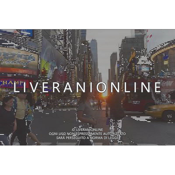 Visitors to Times Square in New York pass the Manhattanhenge sunset on Monday, May 30, 2011. Twice a year, this year on May 30 and July 12, the sun lines up at sunset with the city\'s grid, lighting up both sides of the street and setting in the middle of the roadways. The event, the name coined by Neil deGrasse Tyson of the Hayden Planetarium, takes place 22 days before and 21 days after the summer solstice because of the 30 degree angle of the city\'s grid, it is not exactly east-west-north-south. ©photoshot/Agenzia Aldo Liverani Sas - ITALY ONLY - Gli abitanti e Turisti a New York affollano la citta\' nell\'inizio non ufficiale dell\'estate