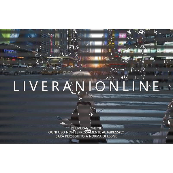 Visitors to Times Square in New York pass the Manhattanhenge sunset on Monday, May 30, 2011. Twice a year, this year on May 30 and July 12, the sun lines up at sunset with the city\'s grid, lighting up both sides of the street and setting in the middle of the roadways. The event, the name coined by Neil deGrasse Tyson of the Hayden Planetarium, takes place 22 days before and 21 days after the summer solstice because of the 30 degree angle of the city\'s grid, it is not exactly east-west-north-south. (å© Richard B. Levine ©photoshot/Agenzia Aldo Liverani Sas - ITALY ONLY - Gli abitanti e Turisti a New York affollano la citta\' nell\'inizio non ufficiale dell\'estate