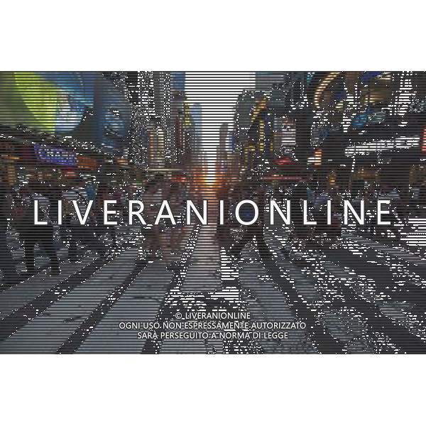 Visitors to Times Square in New York pass the Manhattanhenge sunset on Monday, May 30, 2011. Twice a year, this year on May 30 and July 12, the sun lines up at sunset with the city\'s grid, lighting up both sides of the street and setting in the middle of the roadways. The event, the name coined by Neil deGrasse Tyson of the Hayden Planetarium, takes place 22 days before and 21 days after the summer solstice because of the 30 degree angle of the city\'s grid, it is not exactly east-west-north-south. (å© Richard B. Levine ©photoshot/Agenzia Aldo Liverani Sas - ITALY ONLY - Gli abitanti e Turisti a New York affollano la citta\' nell\'inizio non ufficiale dell\'estate