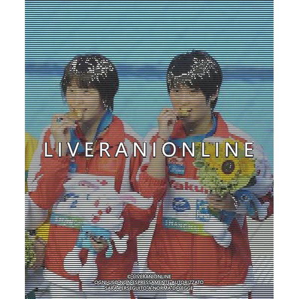 SHANGHAI, July 18, 2011 Wang Hao/Chen Ruolin (R) of China bite their gold medal at the awarding ceremony of the women\'s 10m synchronized platform diving event at the 14th FINA World Championships in Shanghai, east China, July 18, 2011. Wang Hao/Chen Ruolin of China claimed the title with 362.58 points. (/Guo Yong)(zgp)