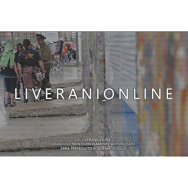 (110810) -- BERLIN, August 10, 2011 () -- A peddler dressed as a former border police (R) makes business with tourists at Potsdamer Platz in Berlin, capital of Germany on August 1, 2011. Berlin is marking the 50th anniversary of the Berlin Wall, which started building on August 13, 1961. (/Ma Ning)