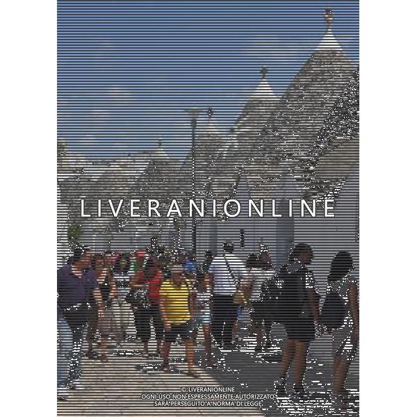 (110812) ALBEROBELLO, Aug. 12, 2011 Tourists stroll around the Trulli in Alberobello, southern Italy, Aug. 10, 2011. Alberobello, the city of drystone dwellings known as trulli, is an exceptional example of vernacular architecture. The trulli are made of roughly worked limestone boulders collected from neighbouring fields. Characteristically, they feature pyramidal, domed or conical roofs built up of corbelled limestone slabs. UNESCO inscribed the Trulli of Alberobello in the World Heritage List in 1996. (/Wang Qingqin)