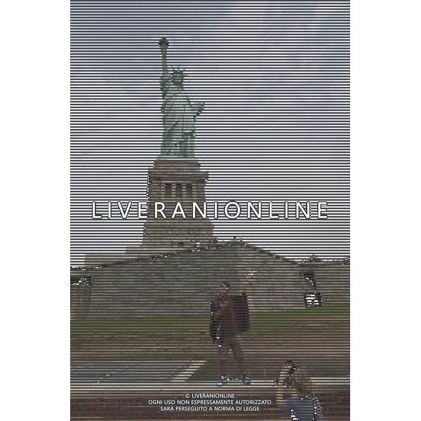 (110819) -- NEW YORK, Aug. 19, 2011 () -- A man poses for photos in front of the Statue of Liberty on Liberty Island in New York, the United States, on Aug. 19, 2011. The Statue of Liberty will be closed for a year at the end of October as it undergoes a $27.25 million renovation. The renovation will take place after Oct 28, the 125th anniversary of the statue. Liberty Island will remain open.(/Fan Xia)