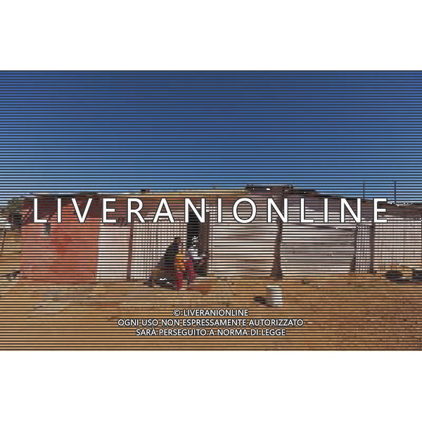 (110831) -- JOHANNESBURG, Aug. 31, 2011 () -- Similo Mathe (R) sits in front of his sheet iron house with her children and a friend at the Ramseg Informal settlement in Johannesburg, South Africa, Aug. 24, 2011. One of the most common landscapes in Johannesburg and even the whole South Africa is slum, some of which stretche for miles and are populated with hundreds and thousands of people. For most of the inhabitants, their houses are made from scrap materials such as wooden stakes or corrugated metal. Although living in a shanty town, poverty cannot stop their pursuit for beauty, nor ruin their impulse in life. Therefore, they find a way to express their love for life, to painting on the iron sheet house. (/Fei Maohua) (msq)