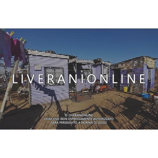 (110831) -- JOHANNESBURG, Aug. 31, 2011 () -- Ntombi Ngcobo and her daughters sit in front of their sheet iron house at the Motswaledi Informal settlement in Soweto, Johannesburg, South Africa, Aug. 24, 2011. One of the most common landscapes in Johannesburg and even the whole South Africa is slum, some of which stretche for miles and are populated with hundreds and thousands of people. For most of the inhabitants, their houses are made from scrap materials such as wooden stakes or corrugated metal. Although living in a shanty town, poverty cannot stop their pursuit for beauty, nor ruin their impulse in life. Therefore, they find a way to express their love for life, to painting on the iron sheet house.(/Fei Maohua) (msq)