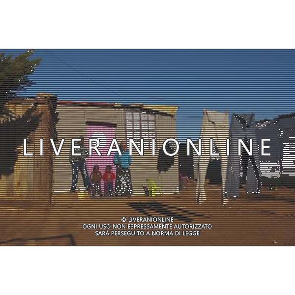 (110831) -- JOHANNESBURG, Aug. 31, 2011 () -- Pamela Nudwana and her children stand in front of their sheet iron house at the Motswaledi Informal settlement in Soweto, Johannesburg, South Africa, Aug. 24, 2011. One of the most common landscapes in Johannesburg and even the whole South Africa is slum, some of which stretche for miles and are populated with hundreds and thousands of people. For most of the inhabitants, their houses are made from scrap materials such as wooden stakes or corrugated metal. Although living in a shanty town, poverty cannot stop their pursuit for beauty, nor ruin their impulse in life. Therefore, they find a way to express their love for life, to painting on the iron sheet house.(/Fei Maohua) (msq)