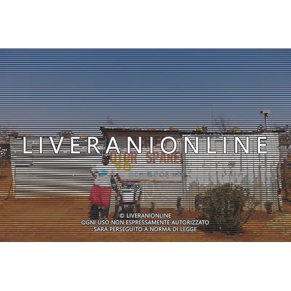 (110831) -- JOHANNESBURG, Aug. 31, 2011 () -- Getrude Abrahams stands in front of her sheet iron house at the Mritini Informal settlement, Johannesburg, South Africa, Aug. 25, 2011. One of the most common landscapes in Johannesburg and even the whole South Africa is slum, some of which stretche for miles and are populated with hundreds and thousands of people. For most of the inhabitants, their houses are made from scrap materials such as wooden stakes or corrugated metal. Although living in a shanty town, poverty cannot stop their pursuit for beauty, nor ruin their impulse in life. Therefore, they find a way to express their love for life, to painting on the iron sheet house.(/Fei Maohua) (msq)