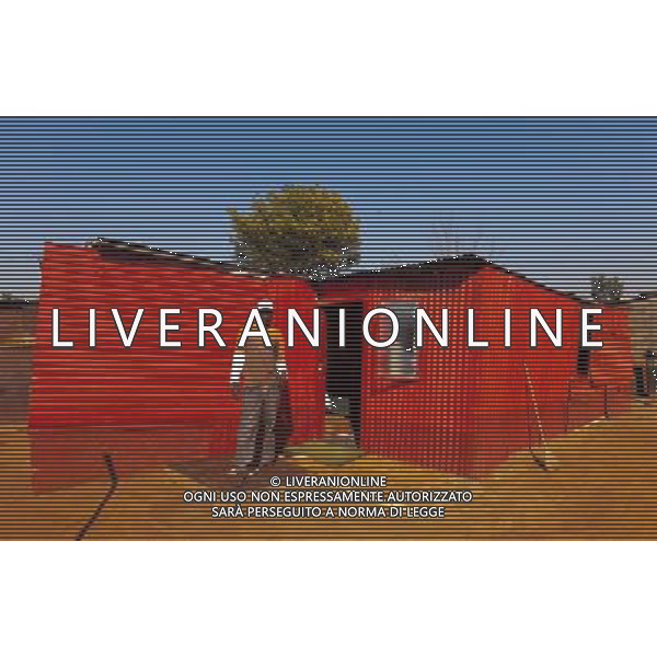 (110831) -- JOHANNESBURG, Aug. 31, 2011 () -- John Kwata stands in front of his sheet iron house at the Thembelihle Informal settlement, Johannesburg, South Africa, Aug. 25, 2011. One of the most common landscapes in Johannesburg and even the whole South Africa is slum, some of which stretch for miles and are populated with hundreds and thousands of people. For most of the inhabitants, their houses are made from scrap materials such as wooden stakes or corrugated metal. Although living in a shanty town, poverty cannot stop their pursuit for beauty, nor ruin their impulse in life. Therefore, they find a way to express their love for life, to painting on the iron sheet house.(/Fei Maohua) (msq)