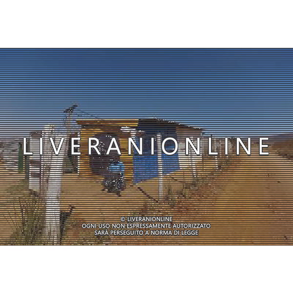 (110831) -- JOHANNESBURG, Aug. 31, 2011 () -- Christinah Neboholo sits in front of her sheet iron house at the Ramseg Informal settlement in Johannesburg, South Africa, Aug. 24, 2011. One of the most common landscapes in Johannesburg and even the whole South Africa is slum, some of which stretche for miles and are populated with hundreds and thousands of people. For most of the inhabitants, their houses are made from scrap materials such as wooden stakes or corrugated metal. Although living in a shanty town, poverty cannot stop their pursuit for beauty, nor ruin their impulse in life. Therefore, they find a way to express their love for life, to painting on the iron sheet house.(/Fei Maohua) (msq)