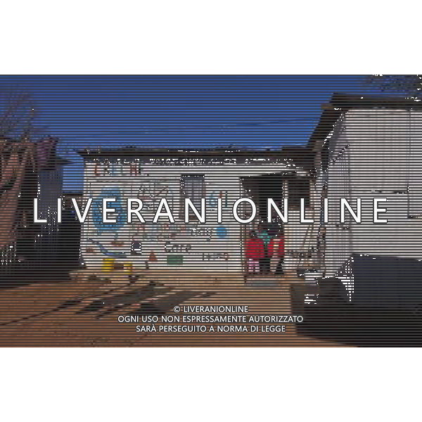 (110831) -- JOHANNESBURG, Aug. 31, 2011 () -- Thuli Hlatshwayo and three children stand in front of a nursery made of his sheet iron house at the Motswaledi Informal settlement in Soweto, Johannesburg, South Africa, Aug. 24, 2011. One of the most common landscapes in Johannesburg and even the whole South Africa is slum, some of which stretche for miles and are populated with hundreds and thousands of people. For most of the inhabitants, their houses are made from scrap materials such as wooden stakes or corrugated metal. Although living in a shanty town, poverty cannot stop their pursuit for beauty, nor ruin their impulse in life. Therefore, they find a way to express their love for life, to painting on the iron sheet house.(/Fei Maohua) (msq)