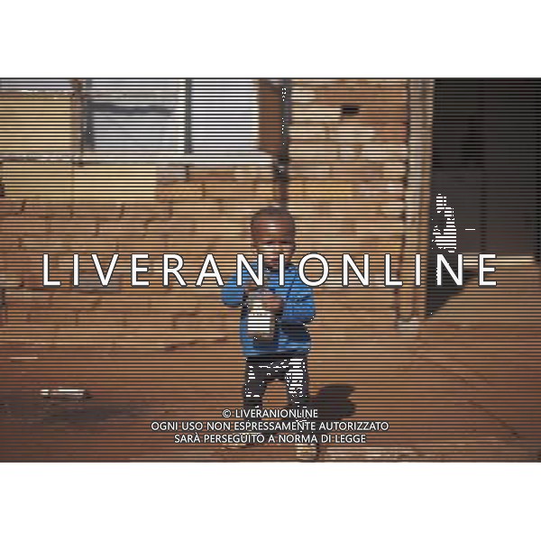 JOHANNESBURG , Sept. 01, 2011 1 year old Phelo holds his toy, a wine bottle, in Thembelihle Informal Settlement, Johannesburg, South Africa, Aug. 25, 2011. Children in the shanty towns don\'t have fancy toys like transformers, barbies or remote control airplanes, but they have a lot of fun playing with a piece of wire, a ball, a discarded circuit board or even a piece of paper. These so called toys bring happiness to the children, though heart breaking it may seem to others. (/Fei Maohua) (xhn)