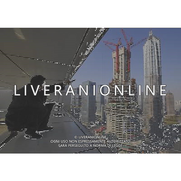 (120117) SHANGHAI, Jan. 17, 2012 () A man points to the Shanghai Tower (front) under construction alongside the Jin Mao Tower and Shanghai World Financial Center in Shanghai, east China, Jan. 17, 2012. Work crews have completed the foundation for the world\'s second tallest building ahead of schedule and are now rushing to construct the ground structure of the 632 meter Shanghai Tower, second only to the 828 meter tall Burj Khalifa in Dubai. () (zgp) ©photoshot/ag aldo liverani italy only