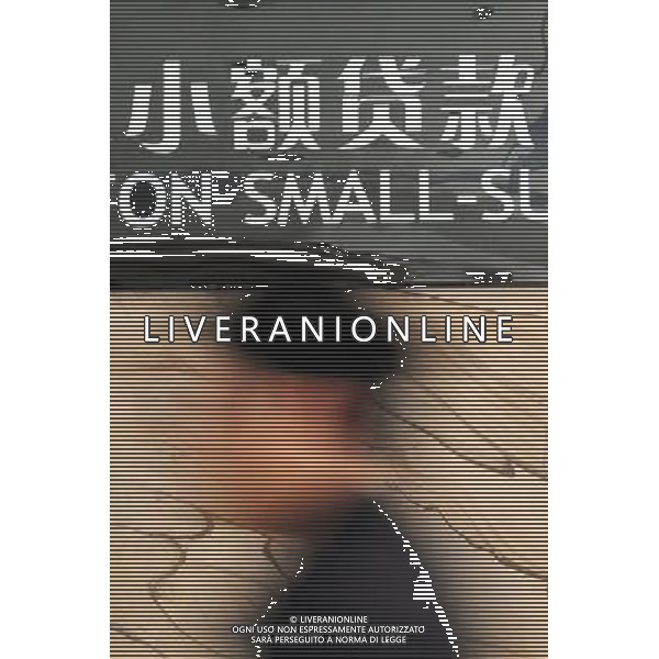 (120328) -- WENZHOU, March 28, 2012 () -- A man walks past the name of a small-sum loan company in Wenzhou, east China\'s Zhejiang Province, March 28, 2012. China has approved plans to set up a pilot zone in the eastern city of Wenzhou to regulate private financing activities, the State Council said Wednesday. The long-awaited decision comes as underground private financing activities in Wenzhou, a major source of funding for the nation\'s small and medium-sized business, have stirred up heated financial disputes and crime and threatened financial and economic stability. Wenzhou, a place full of vibrant business activities, said on March 27, 2012 that the city\'s biggest financial problem lies in liquidity shortage, which is rooted in distrust among companies, banks, and authorities. Wenzhou came into the spotlight earlier last year after reports of cracks appearing in its vast underground lending market and surging bankruptcies. Effectively sorting out Wenzhou\'s problems and making financing serve the real economy are not only important for the healthy development of Wenzhou, but also of great pioneering significance for financial reform and economic development throughout the nation, according to a statement released after a State Council executive meeting presided over by Premier Wen Jiabao on March 28, 2012. (/Wang Dingchang) (zhs) ©photoshot/AGENZIA ALDO LIVERANI SAS - ITALY ONLY - Cina: Veduta della citta\' di Wenzhou, zona pilota per disciplinare le attivita\' di finanziamento privato e per le piccole e medie imprese della nazione, 27 marzo 2012