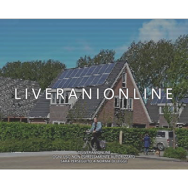 (120606) -- BEIJING, June 6, 2012 () -- Photo taken on May 11, 2012 shows a resident rides his bicycle past a house equipped with solar panels in the City of the Sun community in Heerhugowaard, the Netherlands. City of the Sun, located in Heerhugowaard, north of Amsterdam, capital of the Netherlands, claimed to be the world\'s first and largest carbon-neutral community. The pioneering sustainable housing project has been nominated for the European Urban Planning Award as well as for the Community Sustainability Award from the International City/County Management Association (ICMA) in the United States. City of the Sun, containing some 4,000 residents in 1,500 houses, is entirely energy self-sufficient, creating as much energy as it consumes. All of the dwellings are eco-friendly, featuring solar panels, high-efficiency insulation and heat pumps. Wind turbines situated in the vicinity of the community supply some 7MW of energy, whilst the 50,000 sq meters of solar panels deliver approximately 2.45MW. Besides the sustainable energy sources, the community also uses natural water filtration systems and all homes have water retrieval tanks outside to make use of rainwater. The project contains some 4,000 residents in 1,500 houses.The development has been designed by Dutch architect and urban planner, Ashok Balohtra, who first came up with the idea of a sustainable city almost 20 years ago. One of Balohtra\'s main aims was to create a community that inspired people to lead a more environmental-friendly lifestyle. The name \'City of the Sun\' is a reference to the fact that the majority of the housing is positioned so as to derive maximum yield from solar energy for photovoltaic solar panels (it is also the largest photovoltaic community worldwide). (/Ding Chen) (lr) ©photoshot/AGENZIA ALDO LIVERANI SAS - ITALY ONLY - Pannelli solari fotovoltaici sui tetti delle abitazioni della Citta\' della comunita\' del Sole di Heerhugowaard, a nord di Amsterdam Paesi Bassi in Olanda con circa 4.000 abitanti in 1.500 case, l\'energia e\' interamente autosufficiente, generando energia per ne quanto consuma.