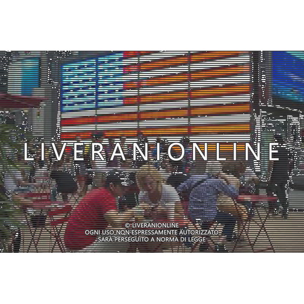 Tourists in front of an electronic American Flag which adorns the sides of the Armed Forces Recruitment booth on Military Island in Times Square, seen on Sunday, September 2, 2012. (å Frances M. Roberts) photoshot/AG ALDO LIVERANI SAS - ITALY ONLY -