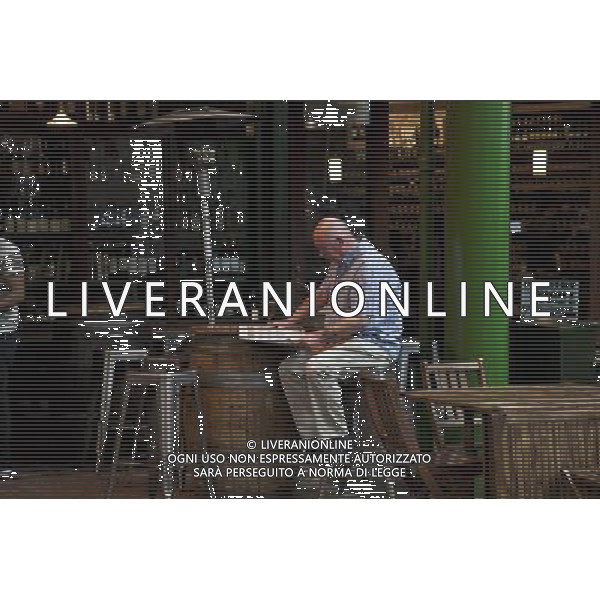 Man reading newspaper and having a drink, Borough Market, London, England AG ALDO LIVERANI S A S ONLY ITALY