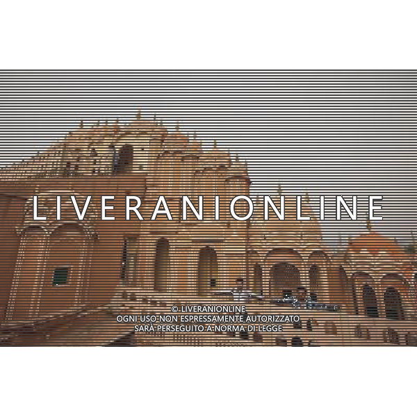 (130613) -- JAIPUR, June 13, 2013 () -- Visitors pose for photo at the Hawa Mahal in Jaipur, capital of Rajasthan, India, June 13, 2013. The Hawa Mahal, also known as Palace of Winds, is a landmark palace in Jaipur. It was built in 1799 from red and pink sandstone with the intention to allow royal ladies to observe life outside the palace. The lattice on the wall was designed to prevent them from being seen, since they followed strict face cover rules. The Hawa Mahal\'s five-storey exterior has 953 small windows, which together with the lattice provides cool air during the high temperatures in summers. (/Zheng Huansong) ©Photoshot/AGENZIA ALDO LIVERANI SAS-ITALY ONLY - EDITORIAL USE ONLY