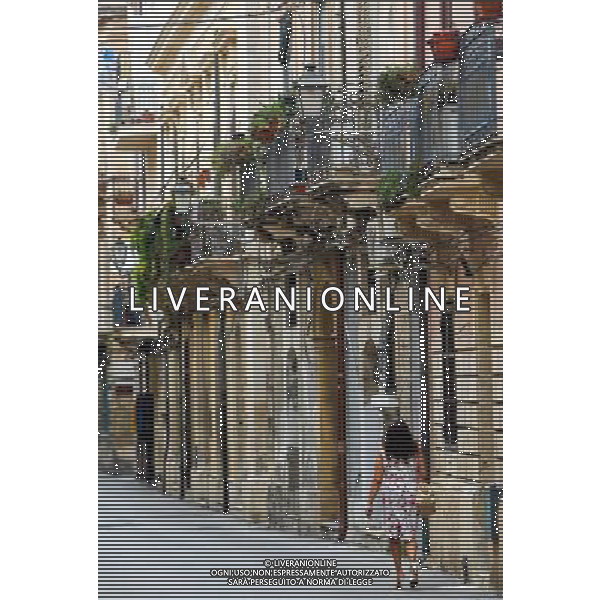 (130920) -- SYRACUSE, Sept. 20, 2013 () -- A lady walks under balconies in Ortigia, the old town of Syracuse in Sicily, Italy, Sept. 5, 2013. Located in the southeast corner of the island of Sicily, Syracuse is a historic city in Italy. The 2,700-year-old city founded in 734 or 733 BC by Greek settlers from Corinth and Tenea played a key role in ancient times when it was one of the major powers of the Mediterranean world. Once described by Cicero, renowned Roman philosopher and orator, as \'the greatest Greek city and the most beautiful of them all\', the city was listed by UNESCO as a World Heritage Site along with the Necropolis of Pantalica in 2005. (/Zhou Lei) ©PHOTOSHOT/AGENZIA ALDO LIVERANI SAS - ITALY ONLY - EDITORIAL USE ONLY