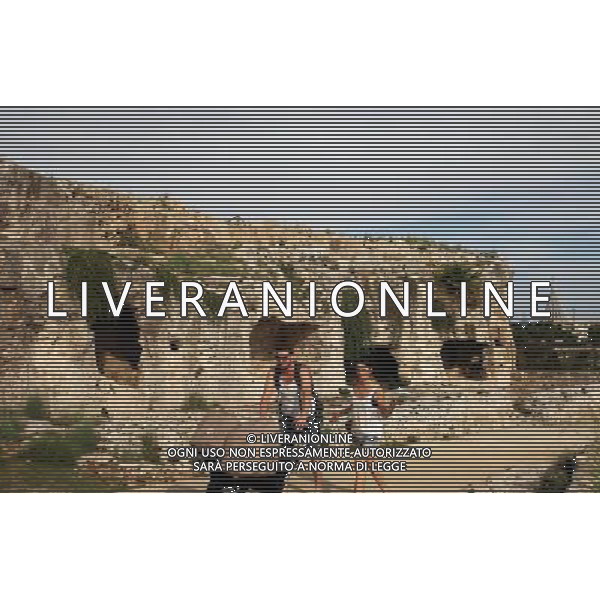 (131008) -- SYRACUSE, Oct. 8, 2013 () -- A couple walk past on Oct. 7, 2013 shows a view of the grave niches on the terrace above the greek theatre in Syracuse, Italy. Ancient Syracuse includes the nucleus of the city\'s foundation as Ortygia by Greeks from Corinth in the 8th century BC. The site of the city, which Cicero described as \'the greatest Greek city and the most beautiful of all\', retains vestiges such as the Temple of Athena (5th century BC, later transformed to serve as a cathedral), a Greek theatre, a Roman amphitheatre, a fort and more. Many remains bear witness to the troubled history of Sicily, from the Byzantines to the Bourbons, interspersed with the Arab-Muslims, the Normans, Frederick II of the Hohenstaufen dynasty (1197--1250), the Aragons and the Kingdom of the Two Sicilies. Historic Syracuse offers a unique testimony to the development of Mediterranean civilization over three millennia. The UNESCO Commitee inscribed Syracuse as a world heritage site in 2005. (/Du Juanjuan) ©photoshot/AGENZIA ALDO LIVERANI SAS - ITALY ONLY - Il Centro storico della citta\' di Siracusa offre una testimonianza unica per lo sviluppo della civilta\' mediterranea oltre tre millenni inscritta dal Comitato UNESCO come sito del patrimonio mondiale nel 2005.