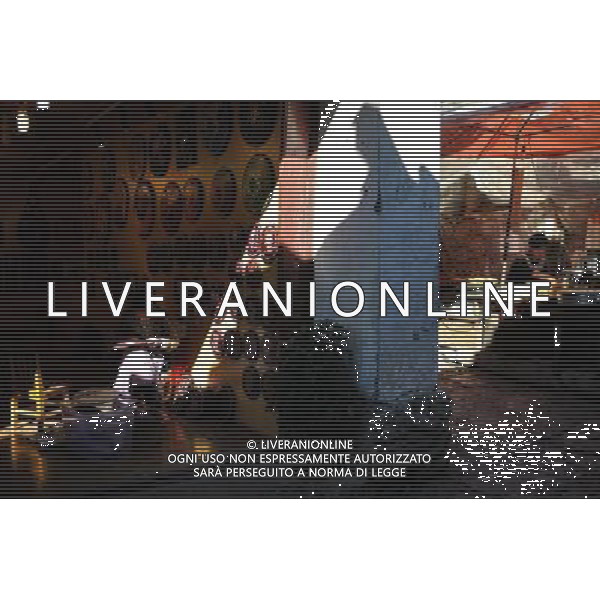 (131112) -- LIJIANG, Nov. 12, 2013 () -- A woman does carving work while a man makes local food outside her store in the old town of Lijiang, southwest China\'s Yunnan Province, Nov. 7, 2013. (/Shen Hong) (mp) ©photoshot/AGENZIA ALDO LIVERANI SAS - ITALY ONLY - La popolazione e le abitazioni della citta\' vecchia di Lijiang, Cina sud-occidentale dello Yunnan Provincia , 6 novembre 2013.