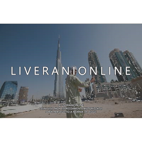 (131127) -- DUBAI, Nov. 27, 2013 () -- Photo taken on Nov. 16, 2013 shows a man looking at his cellphone under the world\'s highest architecture Burj Khalifa tower in Dubai, United Arab Emirates. Dubai won on Wednesday the right to host World Expo 2020 at the 154th General Assembly of the Bureau International des Expositions (BIE) in Paris. (/Cui Xinyu) ©photohsot/AGENZIA ALDO LIVERANI SAS - ITALY ONLY - La citta\' di Dubai, si e\' aggiudicato il diritto di ospitare World Expo 2020 alla 154ma Assemblea Generale del Bureau International des Expositions (BIE), Emirati Arabi Uniti 27 novembre 2013.