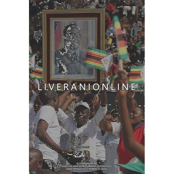 (140811) -- HARARE, Aug. 11, 2014 () -- Zimbabweans hold national flags and a giant photo of President Robert Mugabe at the National Heroes Acre in Harare, Zimbabwe, Aug. 11, 2014. Thousands of people on Monday thronged the National Heroes Acre to mark Heroes Day, a day set aside to honour living and fallen heroes of the war of liberation that freed the country from colonial bondage. (/Stringer) ©PHOTOSHOT/Agenzia Aldo Liverani sas - ITALY ONLY - EDITORIAL USE ONLY - Il presidente dello Zimbabwe Robert Mugabe tiene un discorso al National Heroes Acre Harare, Zimbabwe, 11 Agosto, 2014 giorno dedicato ad onorare viventi e caduti gli eroi della guerra di liberazione che ha liberato il paese dalla schiavitu\' coloniale
