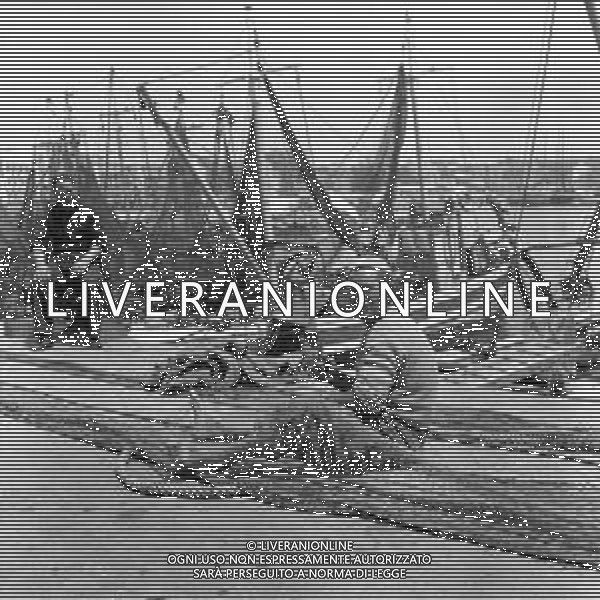 VEDUTE DELLA CITTA\' DI ANZIO LITORALE ROMANO - RETROSPETTIVA 1950 - 1960 Nella foto un pescatore mentre ripara la rete e le barche ormeggiate lungo la banchina del porto ©Archivio Giovanni Liverani / AGENZIA ALDO LIVERANI SAS